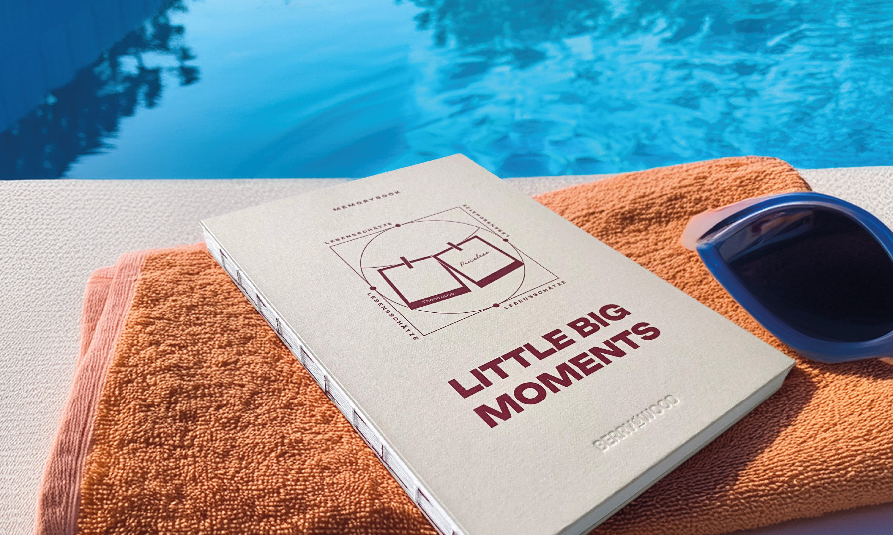 Little Big Moments Journal von Berrywood auf einem Handtuch am Pool, daneben eine Sonnenbrille